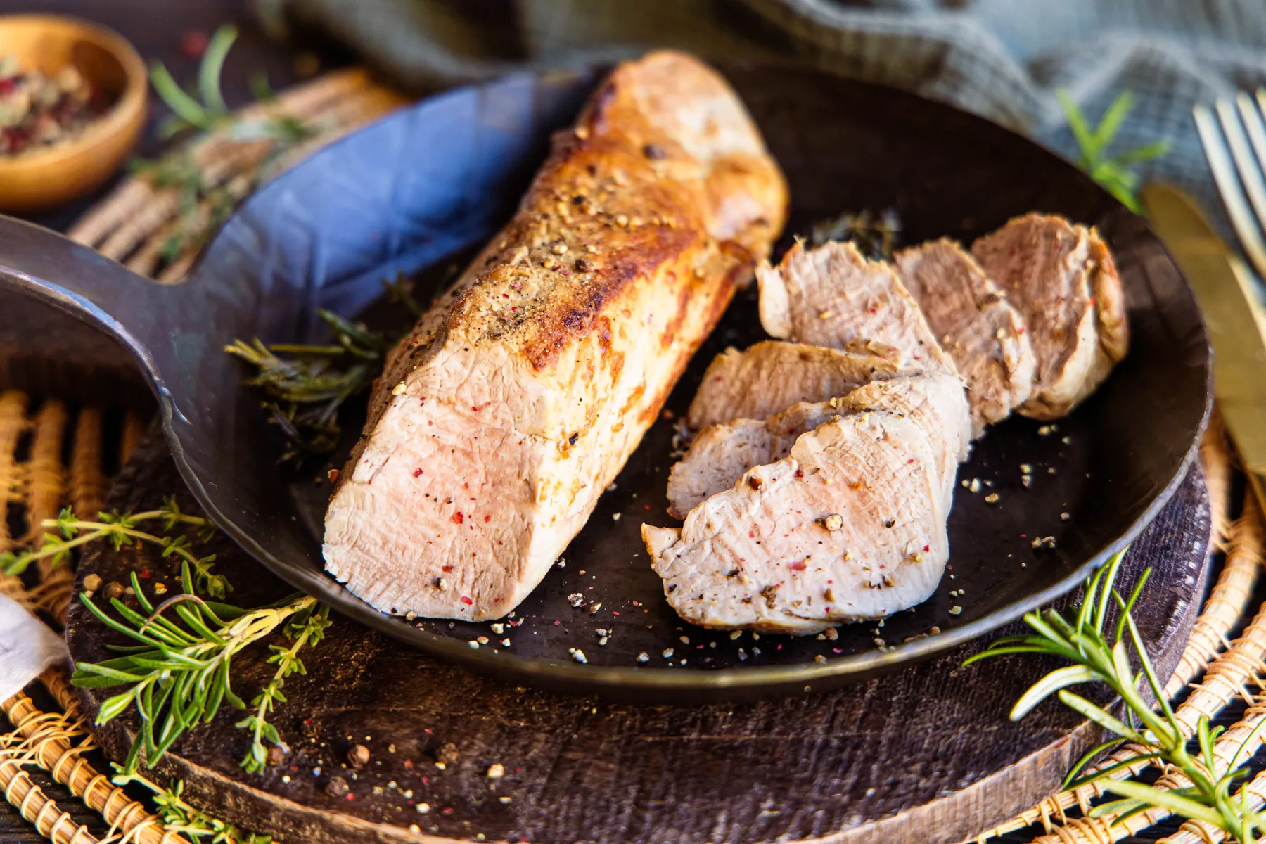 Ein perfekt gebratenes Schweinefilet, bereit zum Servieren mit Beilagen, präsentiert sich zart und saftig.