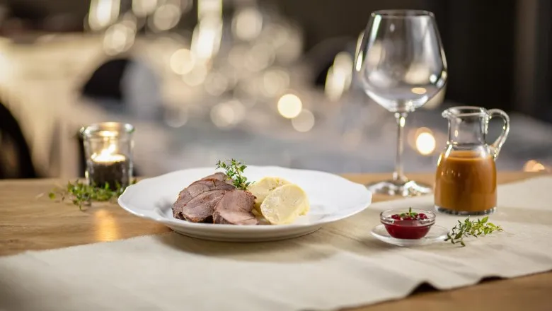 Ein perfekt gegarter Rehbraten mit Serviettenknödeln, übergossen mit reichhaltiger Wildsoße, bereit zum Servieren