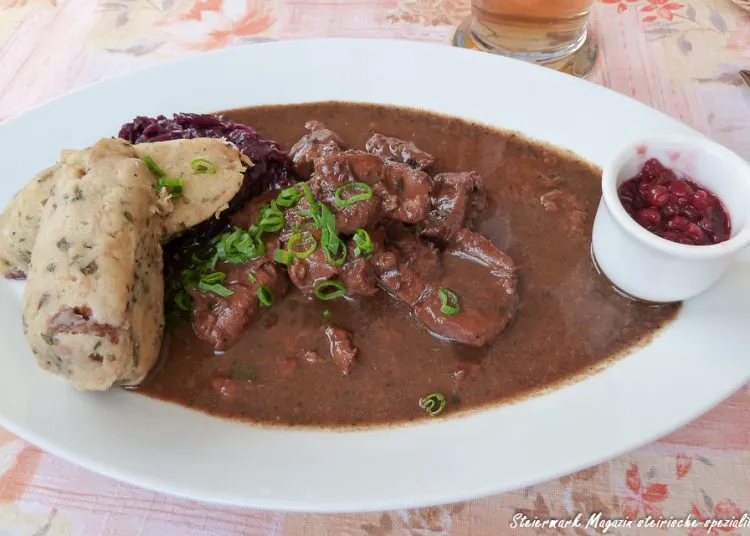 Ein reichhaltiges Hirschgulasch, serviert mit frischen Preiselbeeren und Kräutern