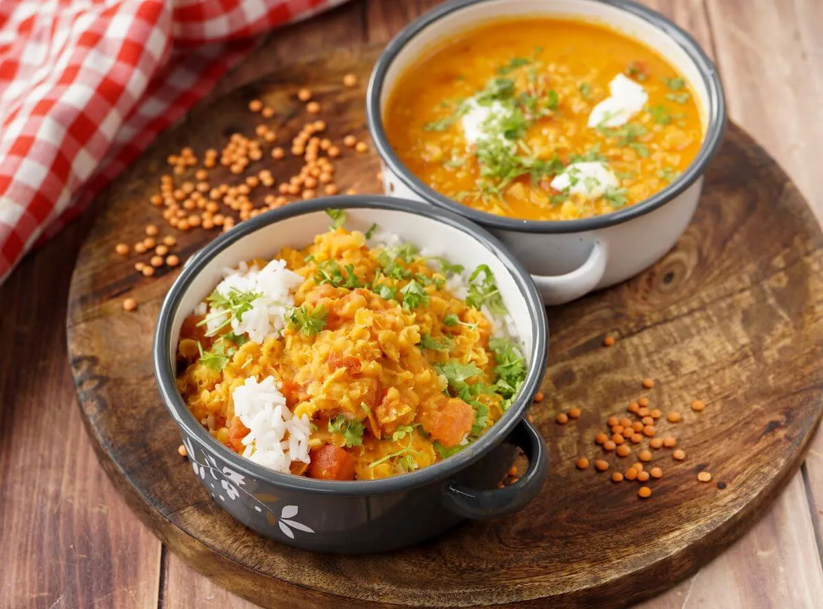 Ein reichhaltiges rotes Linsen Curry mit frischen Kräutern in einer modernen Schüssel