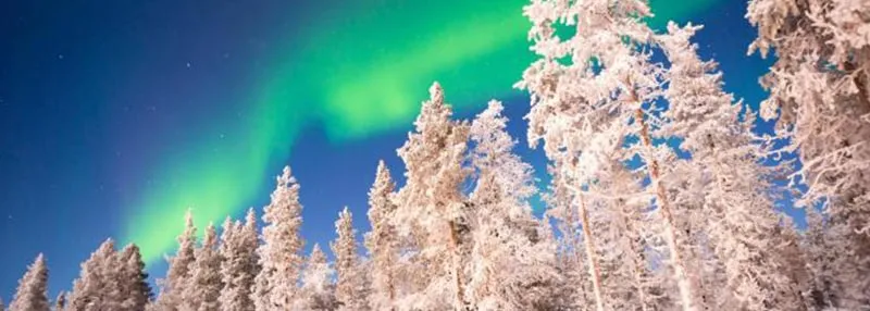 Ein schneebedecktes Lappland mit einem traditionellen Holzhaus unter den Nordlichtern