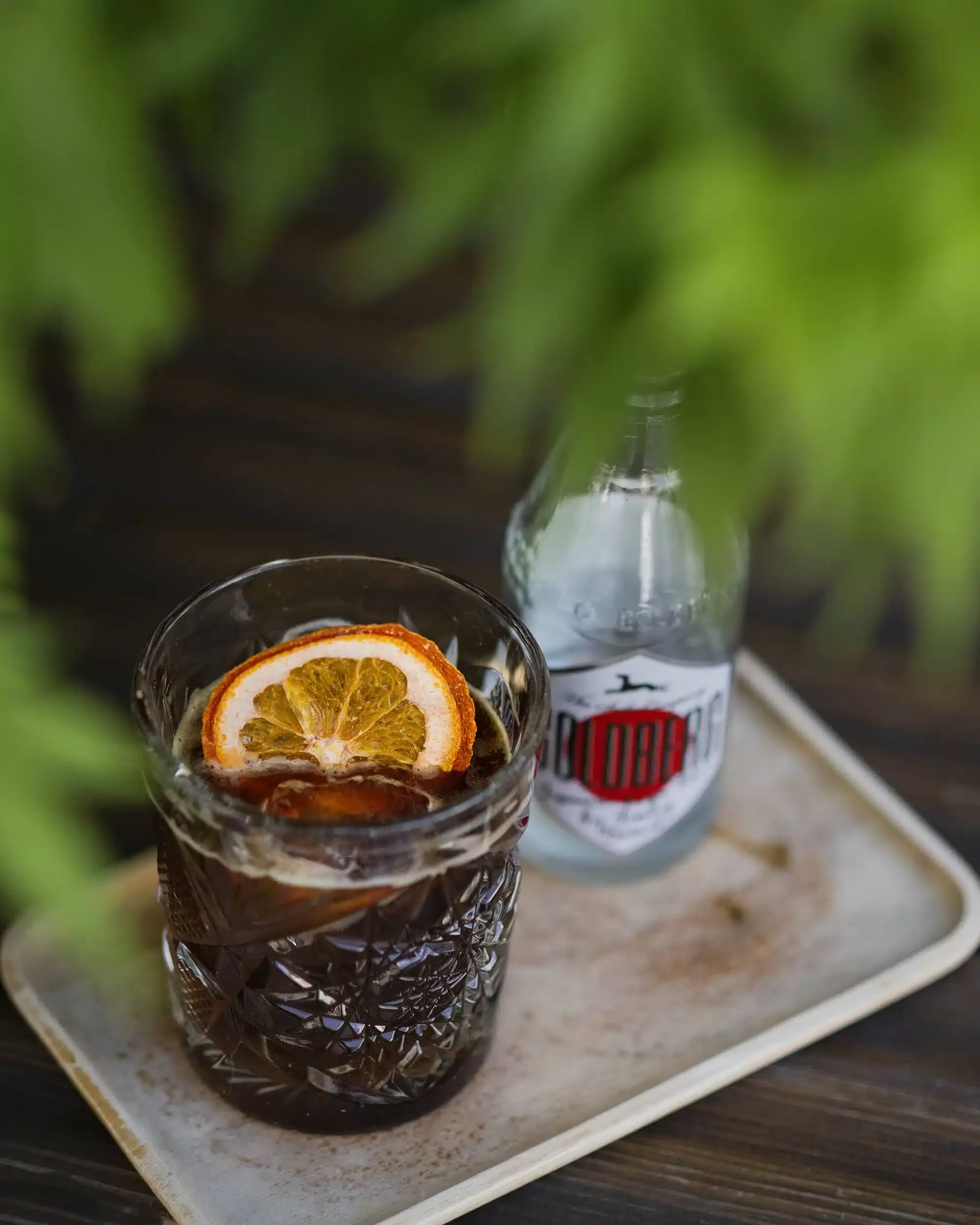 Ein sommerlicher Cold Brew und Yuzu Tonic Drink in einem hohen Glas mit Eis und Orangenzeste