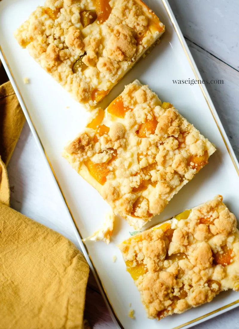 Ein Stück cremiger Quark-Streuselkuchen mit Pfirsichen auf einem Teller