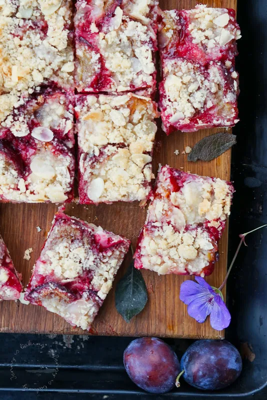 Ein Stück frisch gebackener Pflaumenkuchen auf einem Teller mit Mandeln
