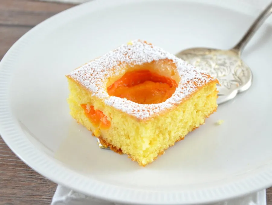 Ein Stück Obstfleck mit Marillen auf einer Tortenplatte serviert.