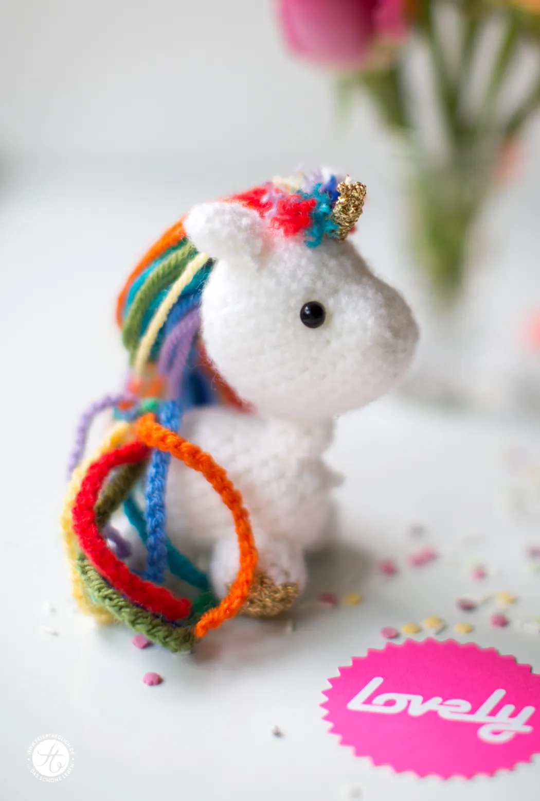 Ein süßes gehäkeltes Einhorn mit Regenbogenmähne und -schwanz, eine kreative Geschenkidee für Geburtstage.