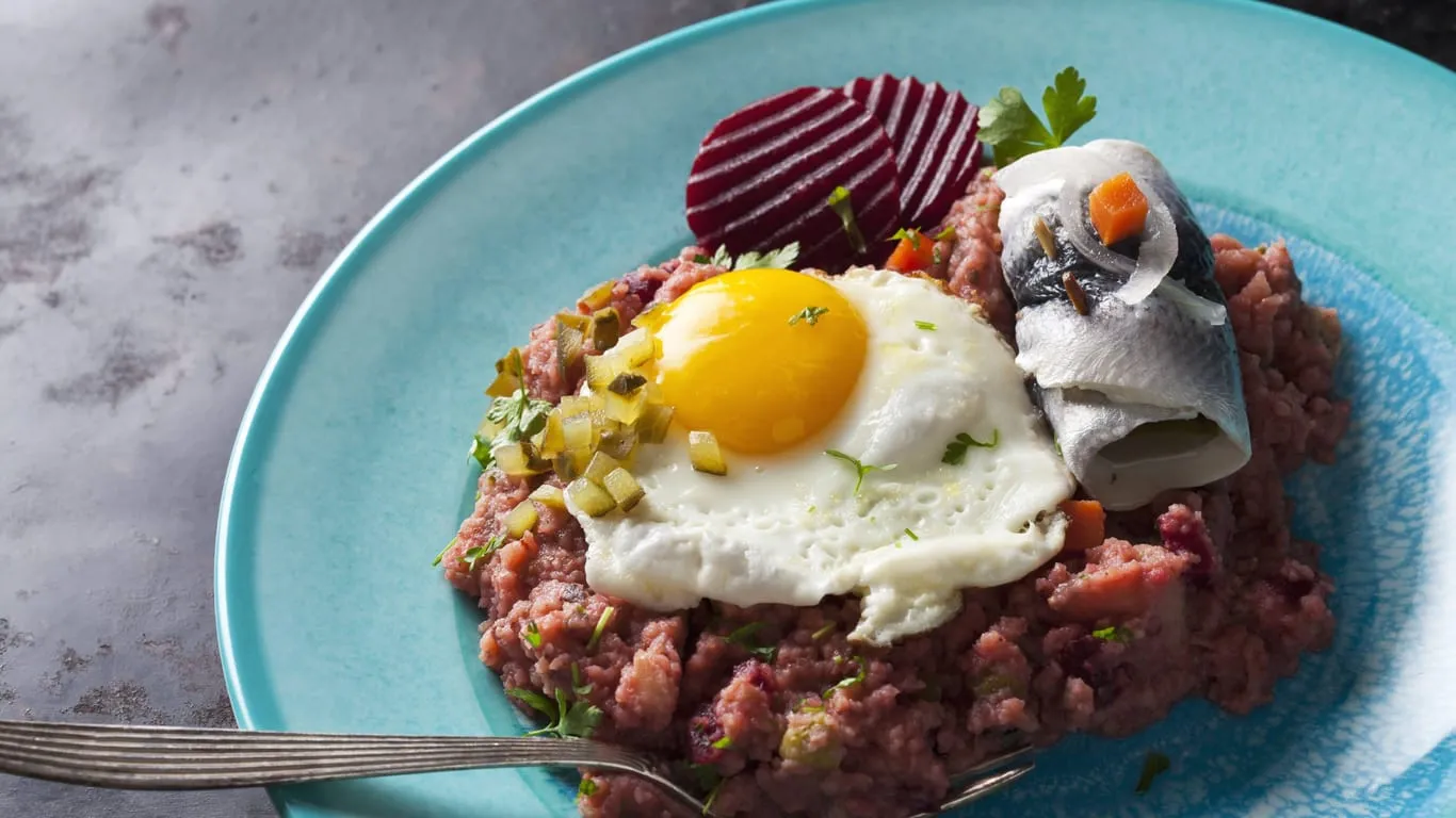 Ein Teller Labskaus mit Kartoffeln, Rollmops, Gewürzgurke, Roter Bete und Spiegelei