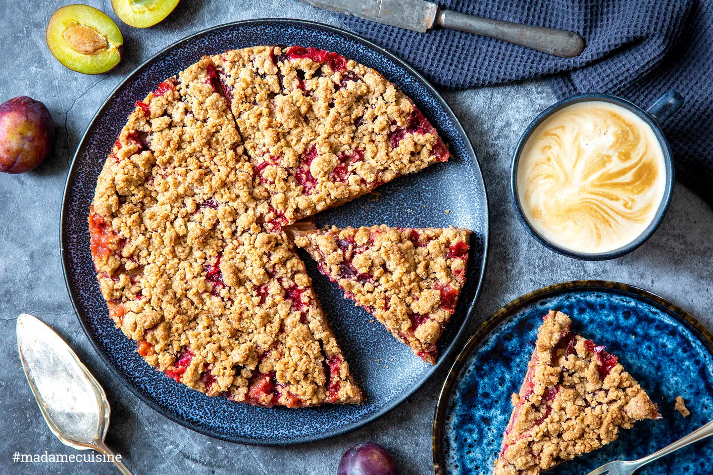 Ein Teller mit einem saftigen Stück Zwetschgenkuchen und einer Tasse duftenden Kaffees.
