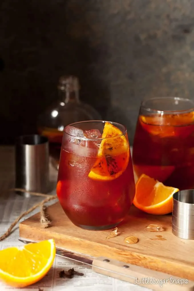 Ein Winter-Gewürz-Negroni, garniert mit einem verkohlten Orangenkeil, der zum Genuss einlädt