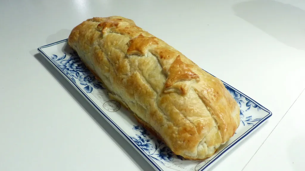 Ein wunderschön angerichtetes Schweinsfilet im Teig, serviert mit frischem Gemüse und Beilagen