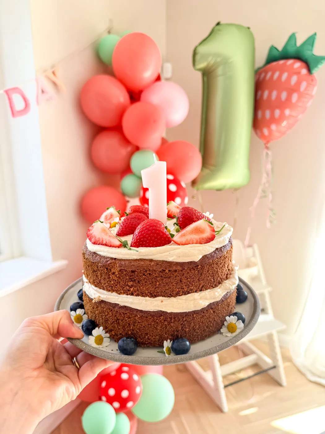 Ein wunderschön dekorierter Geburtstagskuchen für 1-Jährige mit frischen Beeren und essbaren Blüten