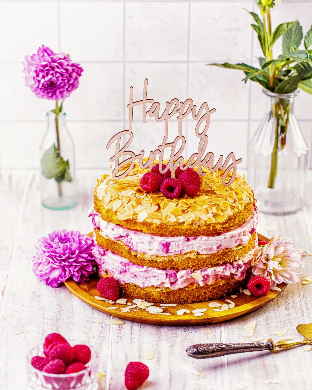 Ein wunderschön dekorierter Himbeer-Quark Naked Cake auf einer Tortenplatte, bereit zum Servieren