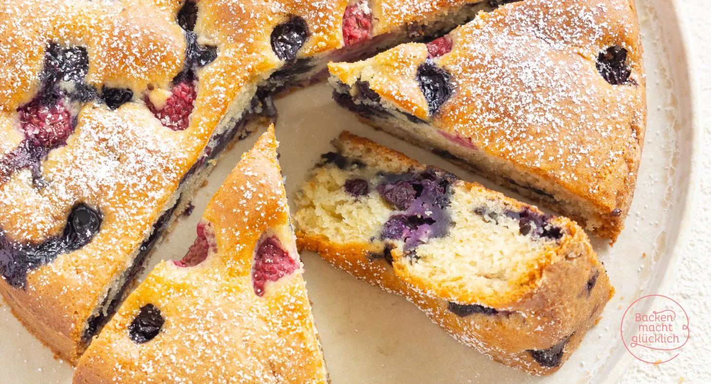 Ein wunderschön dekorierter veganer Beerenkuchen, bestäubt mit Puderzucker und frischen Beeren.