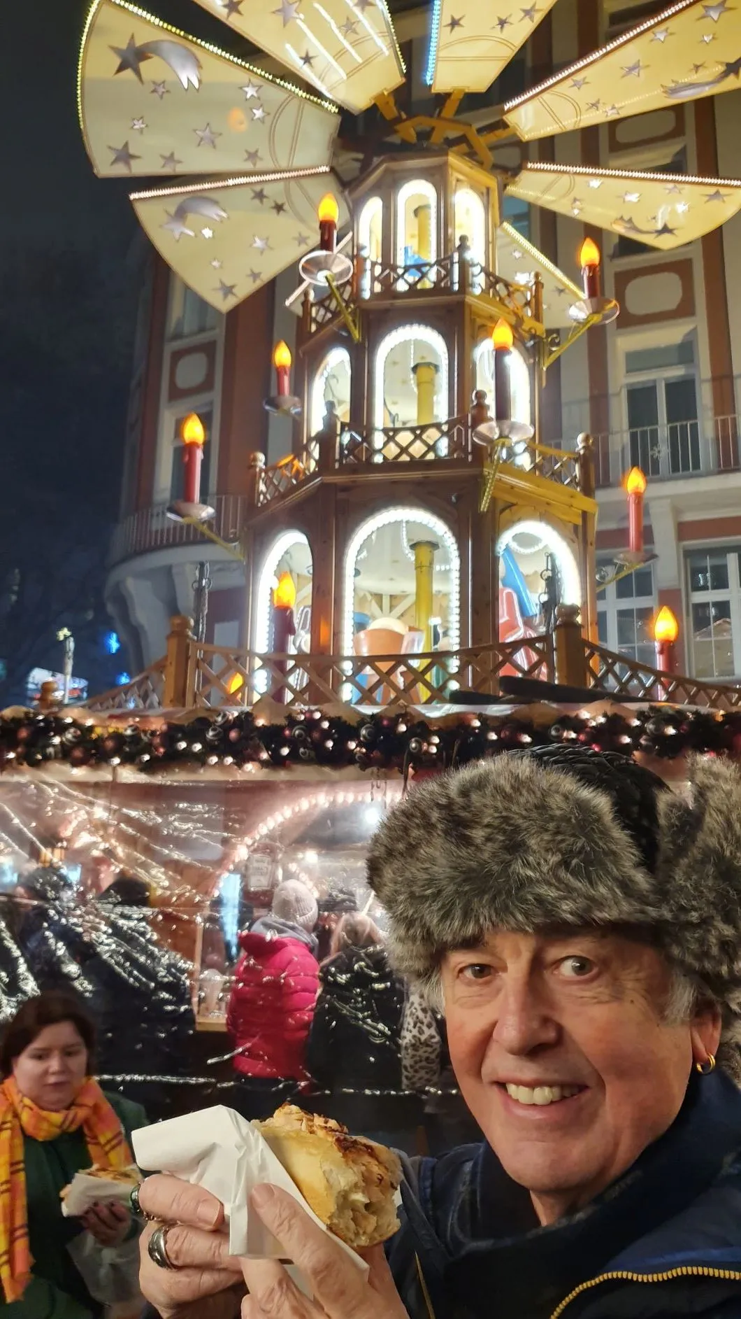 Ein zufriedener Besucher genießt seinen frisch zubereiteten Flammlachs auf einem Weihnachtsmarkt