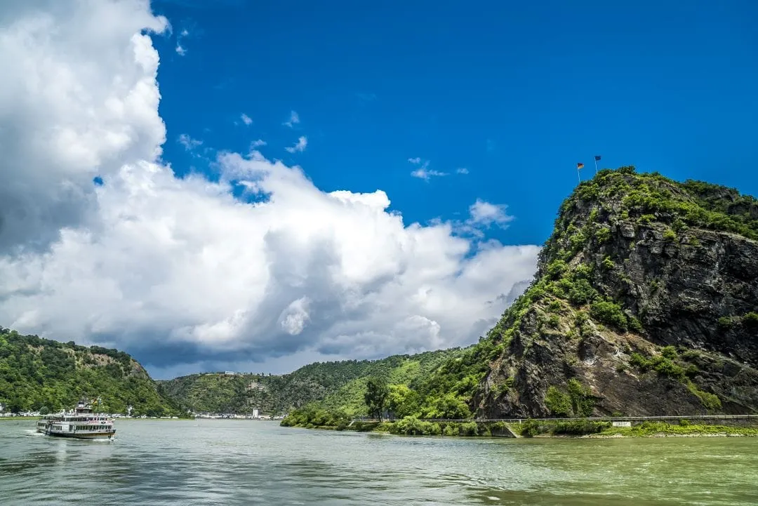 Eine alte Burg auf einem Hügel mit einem Fluss und Weinbergen im Tal.
