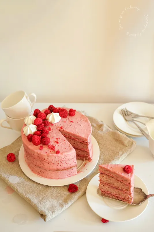 Eine Ansicht des aufgeschnittenen pinken Geburtstagskuchens, der die Himbeer-Füllung und die Schichten des Kuchens zeigt