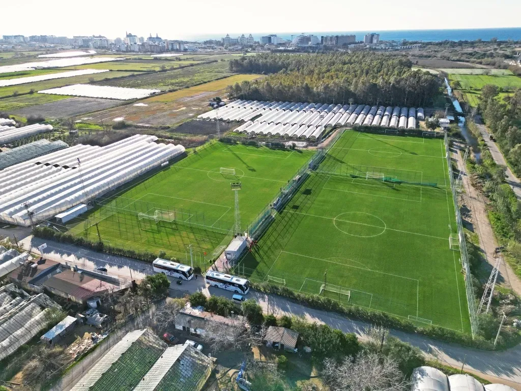 Eine beeindruckende Luftaufnahme einer weitläufigen Sportanlage mit mehreren Fußballfeldern und angrenzenden Hotelgebäuden.