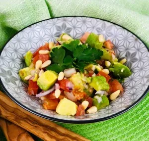 Eine bunte Avocado-Tomaten-Salsa in einer Schale, garniert mit frischen Kräutern, perfekt als Beilage oder Dip