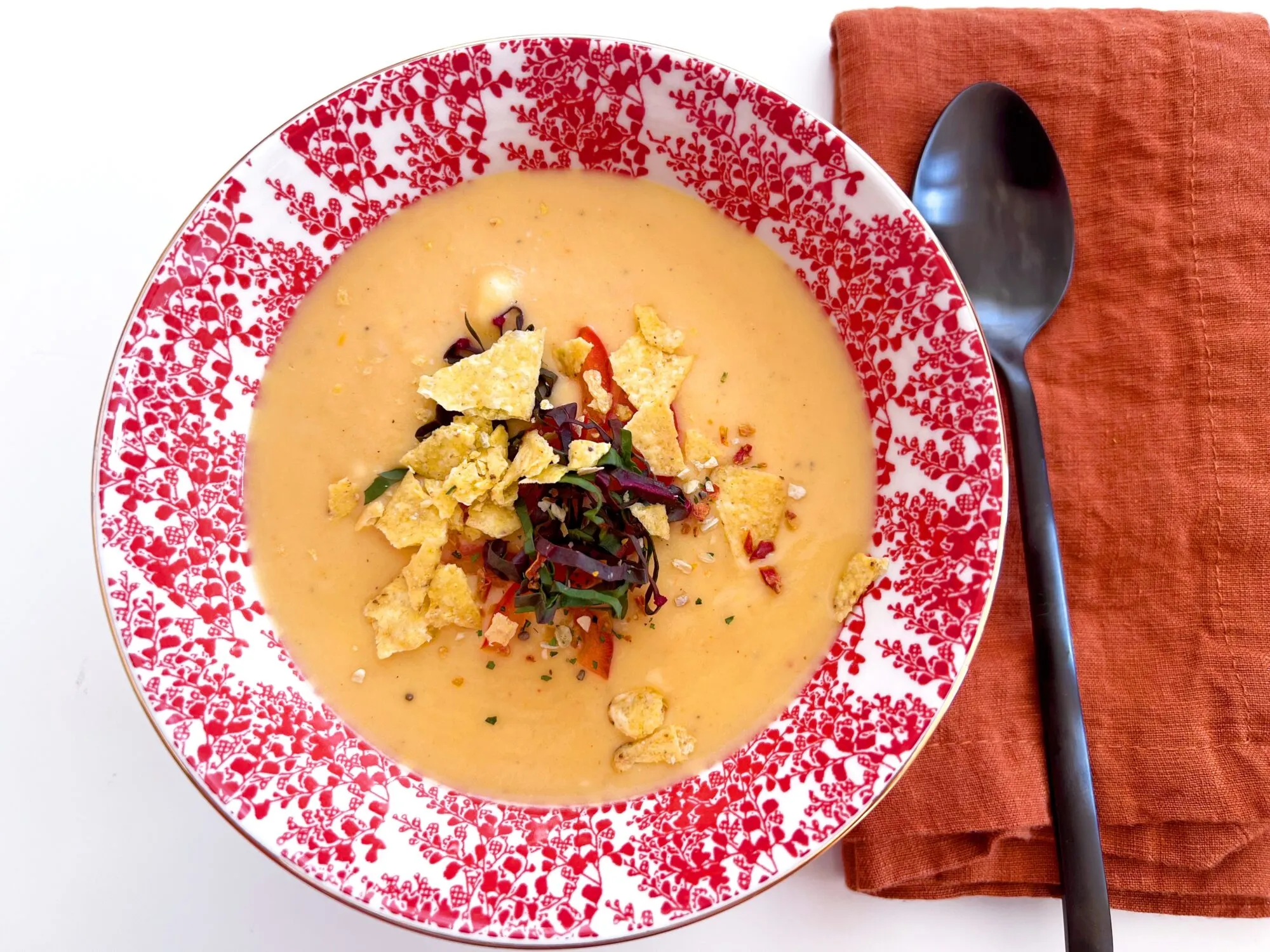 Eine dampfende Schüssel cremiger Käsesuppe, garniert mit Koriander und Nachos