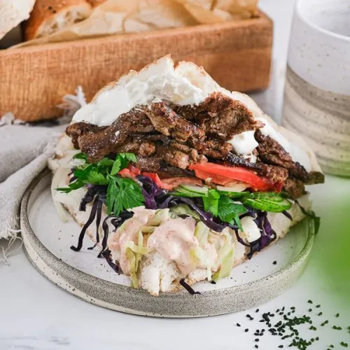 Eine detaillierte Aufnahme der Döner-Zubereitung, mit Fleisch und Gemüse im Fladenbrot