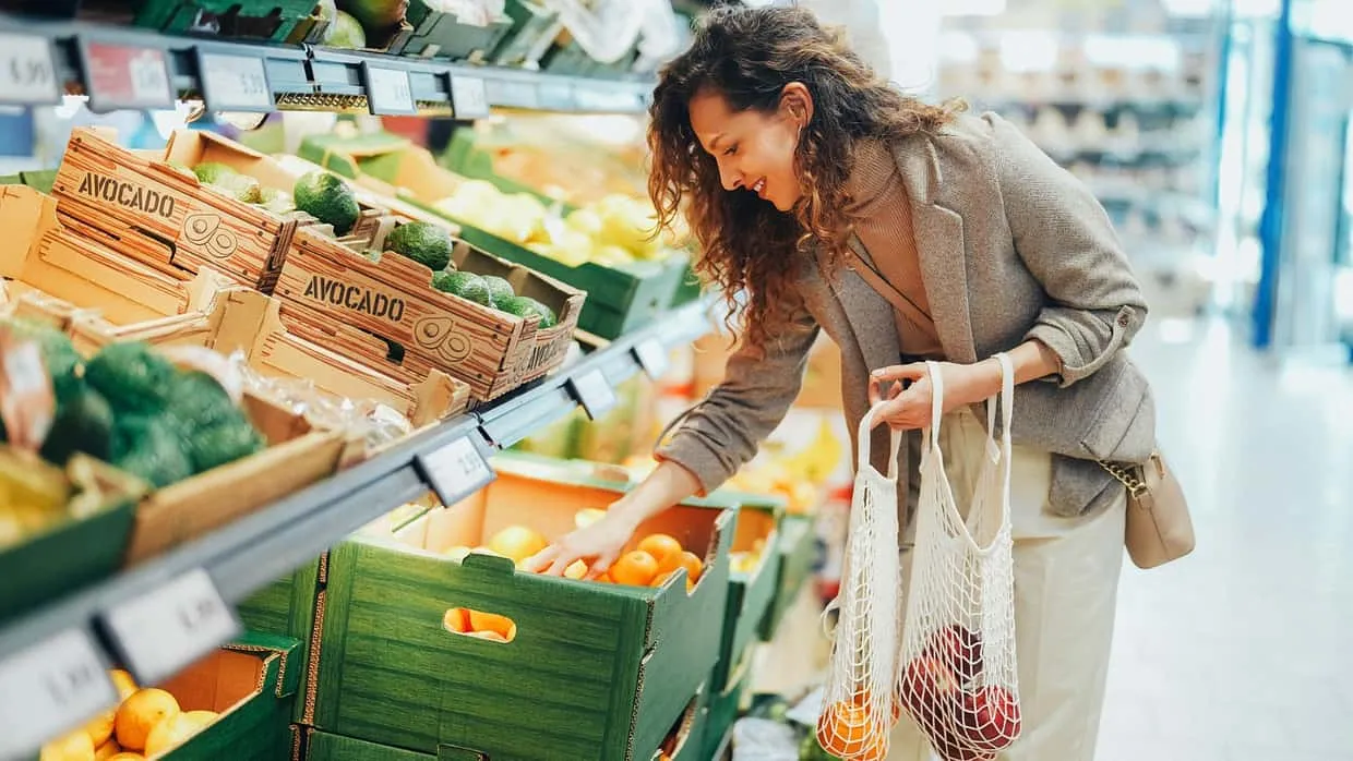 Eine Frau entscheidet sich im Supermarkt für frisches Obst und Gemüse, das eine gesunde Ernährung fördert.