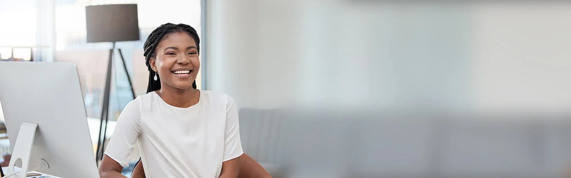 Eine Frau sitzt konzentriert an ihrem Schreibtisch und arbeitet an einem Computer