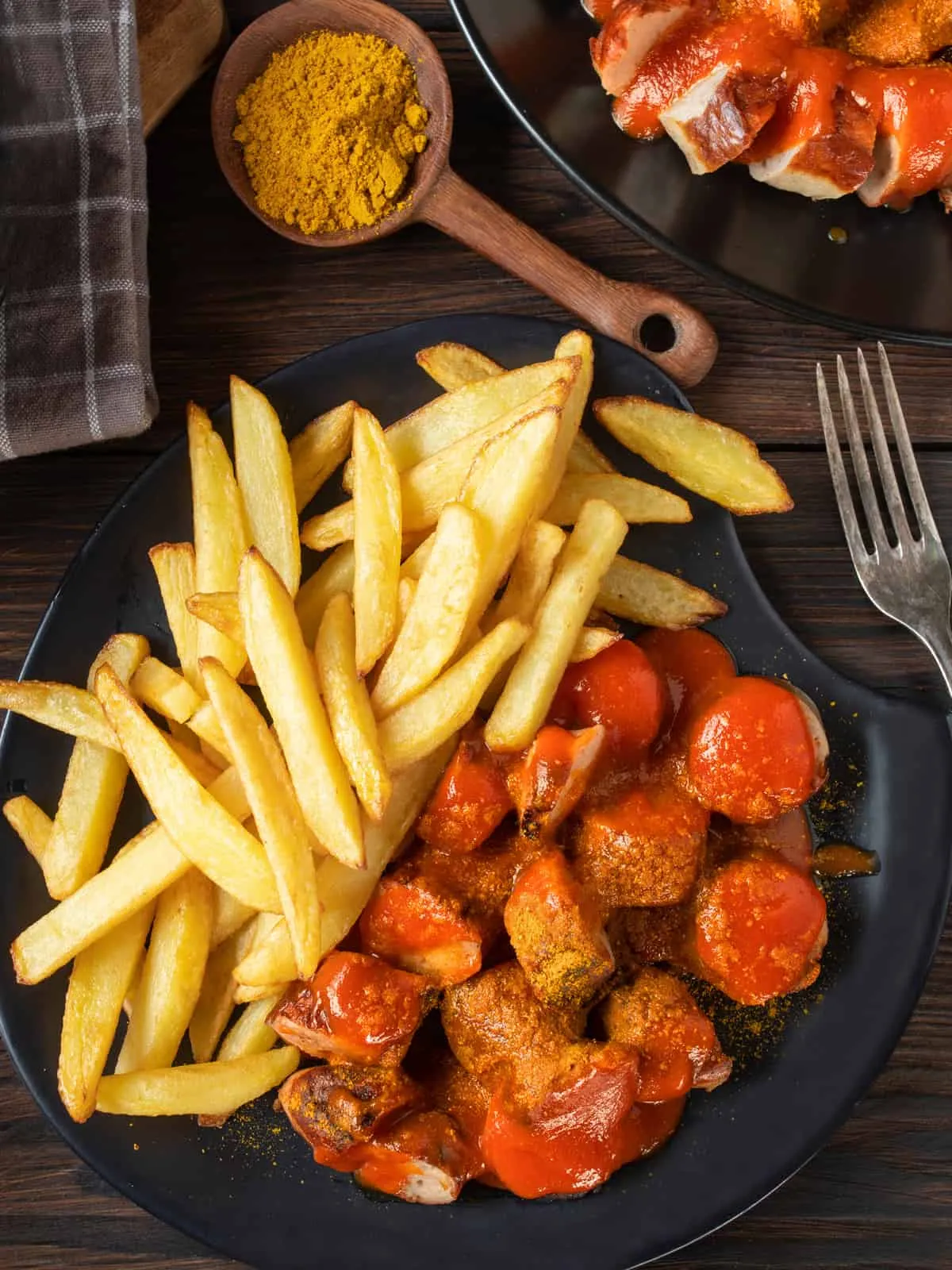 Eine frisch zubereitete Currywurst, serviert mit goldbraunen Pommes Frites in einer klassischen Pappschale