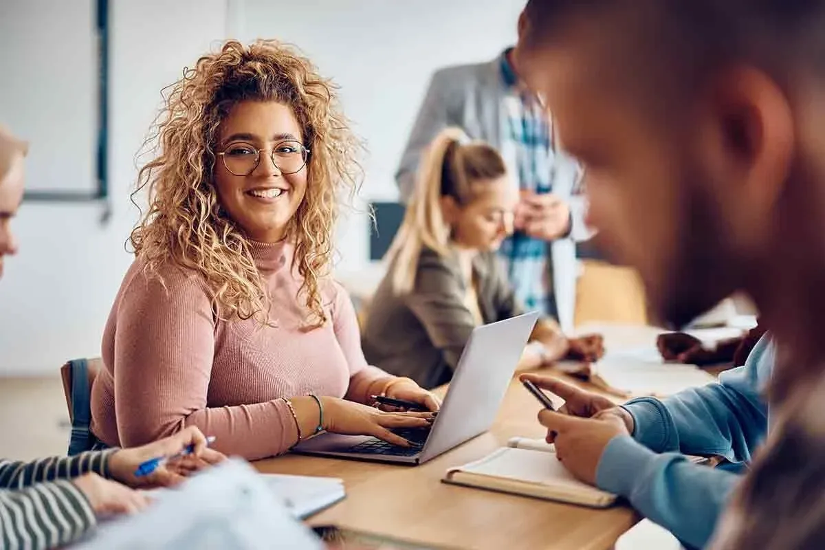 Eine Gruppe von Menschen sitzt an einem Konferenztisch, während zwei Männer sich die Hände schütteln und eine Vereinbarung besiegeln