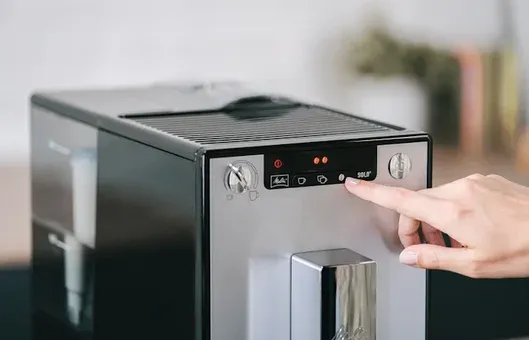Eine Hand bedient das LCD-Textdisplay des Melitta Solo Kaffeevollautomaten