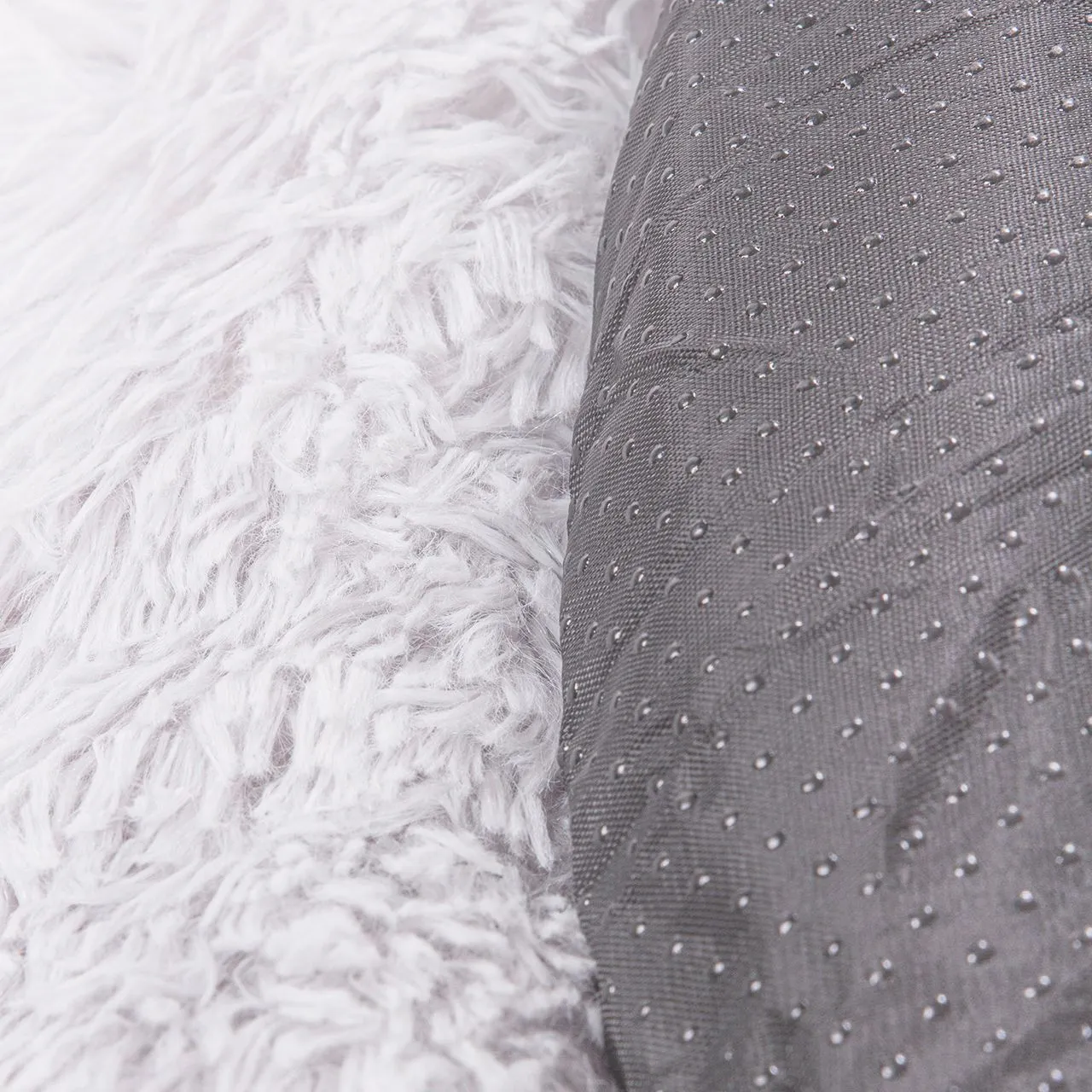 Eine Katze kuschelt sich in das weiche, runde Katzenkörbchen in hellem Grau