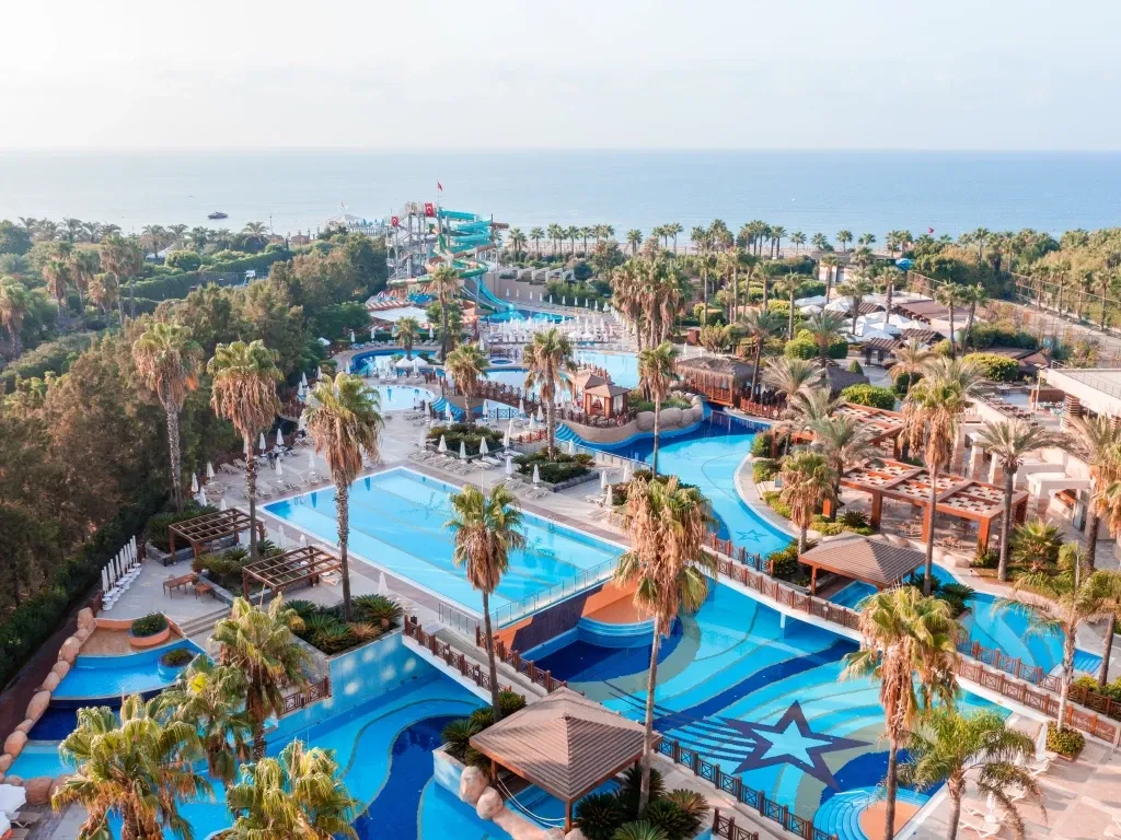 Eine moderne Hotelanlage an der türkischen Küste mit weitläufigen Pools und viel Grünflächen.