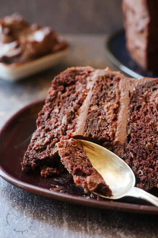 Eine Nahaufnahme eines Stücks Schoko-Zucchini-Torte, serviert mit frischen Himbeeren, die den Kontrast betonen