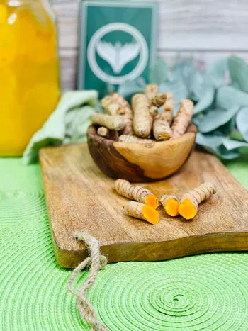 Eine Nahaufnahme von frischen Kurkumaknollen auf einem rustikalen Holzhintergrund, bereit zur Verarbeitung