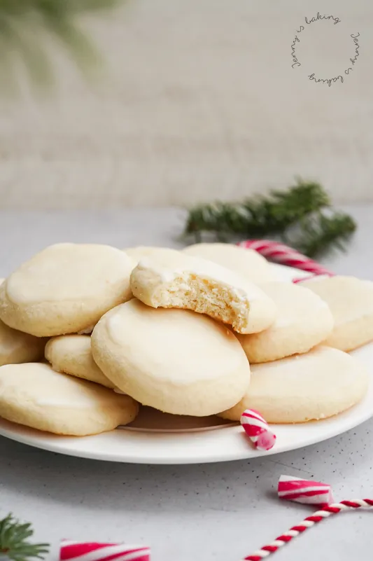 Eine Nahaufnahme von hellen, runden Pfefferminz-Plätzchen mit einer leichten Glasur, auf einem Backrost ausgelegt, daneben frische Pfefferminzblätter zur Dekoration.