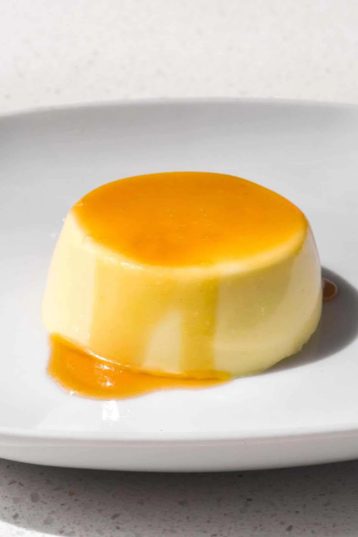 Eine Panna Cotta mit Agar-Agar auf einem weißen Teller, beträufelt mit Butterscotch-Sauce und bestreut mit Meersalzflocken