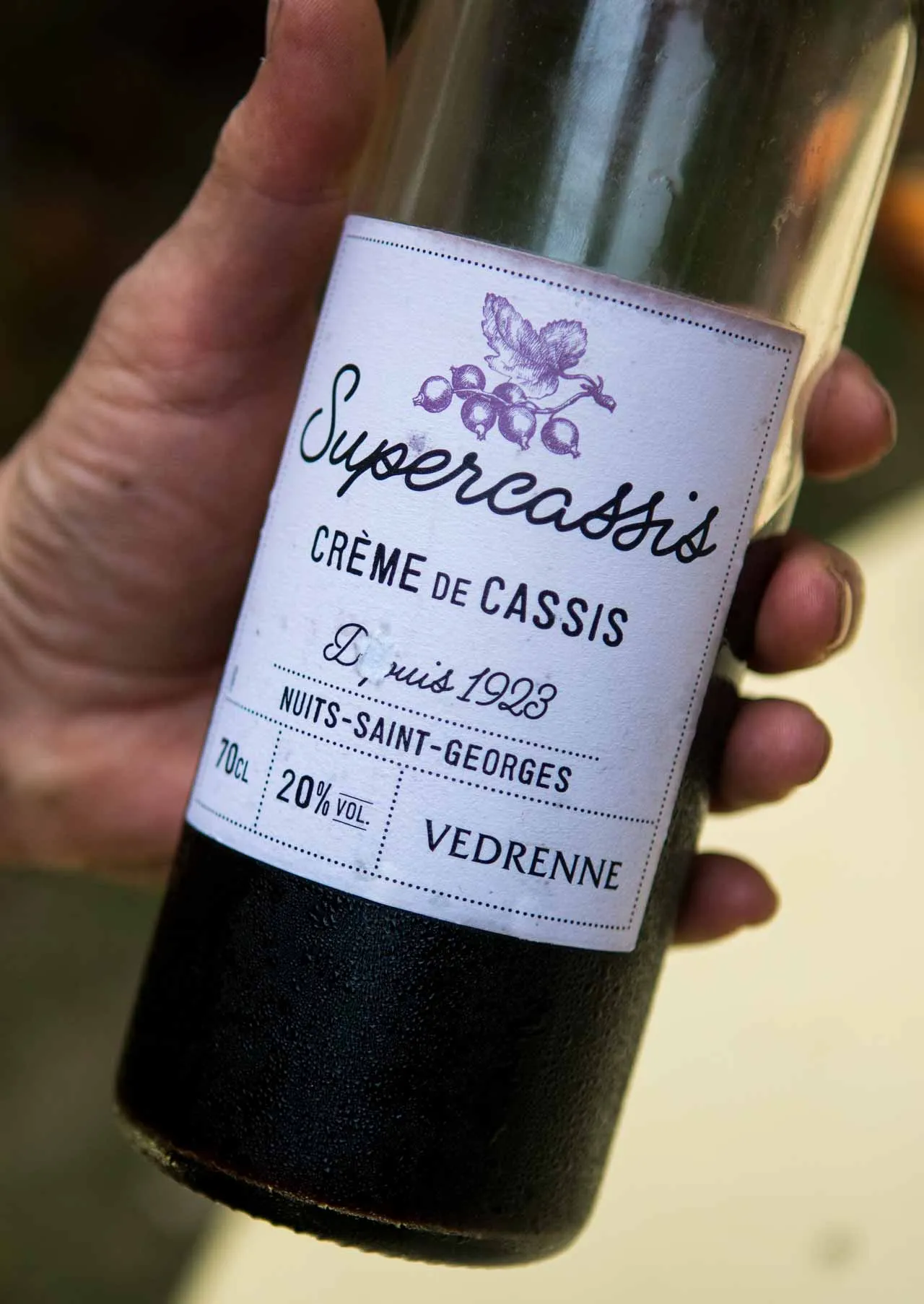 Eine Person hält ein Glas Kir Aperitif in der Hand, während sie in die Ferne blickt