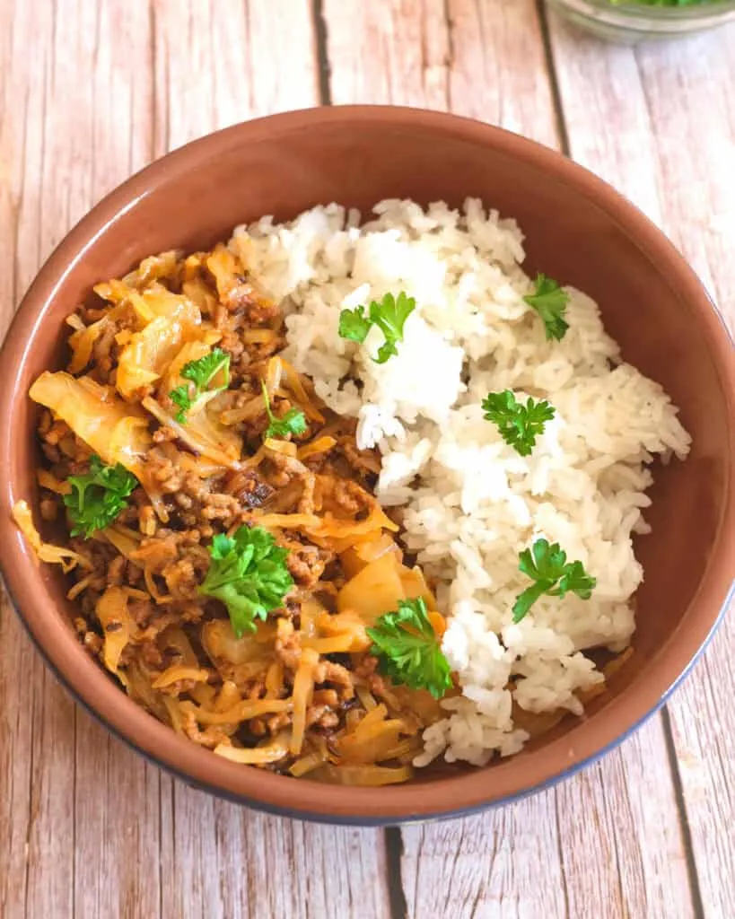 Eine Portion herzhafter Schmorkohl mit Hackfleisch, serviert mit duftendem Reis auf einem Teller.