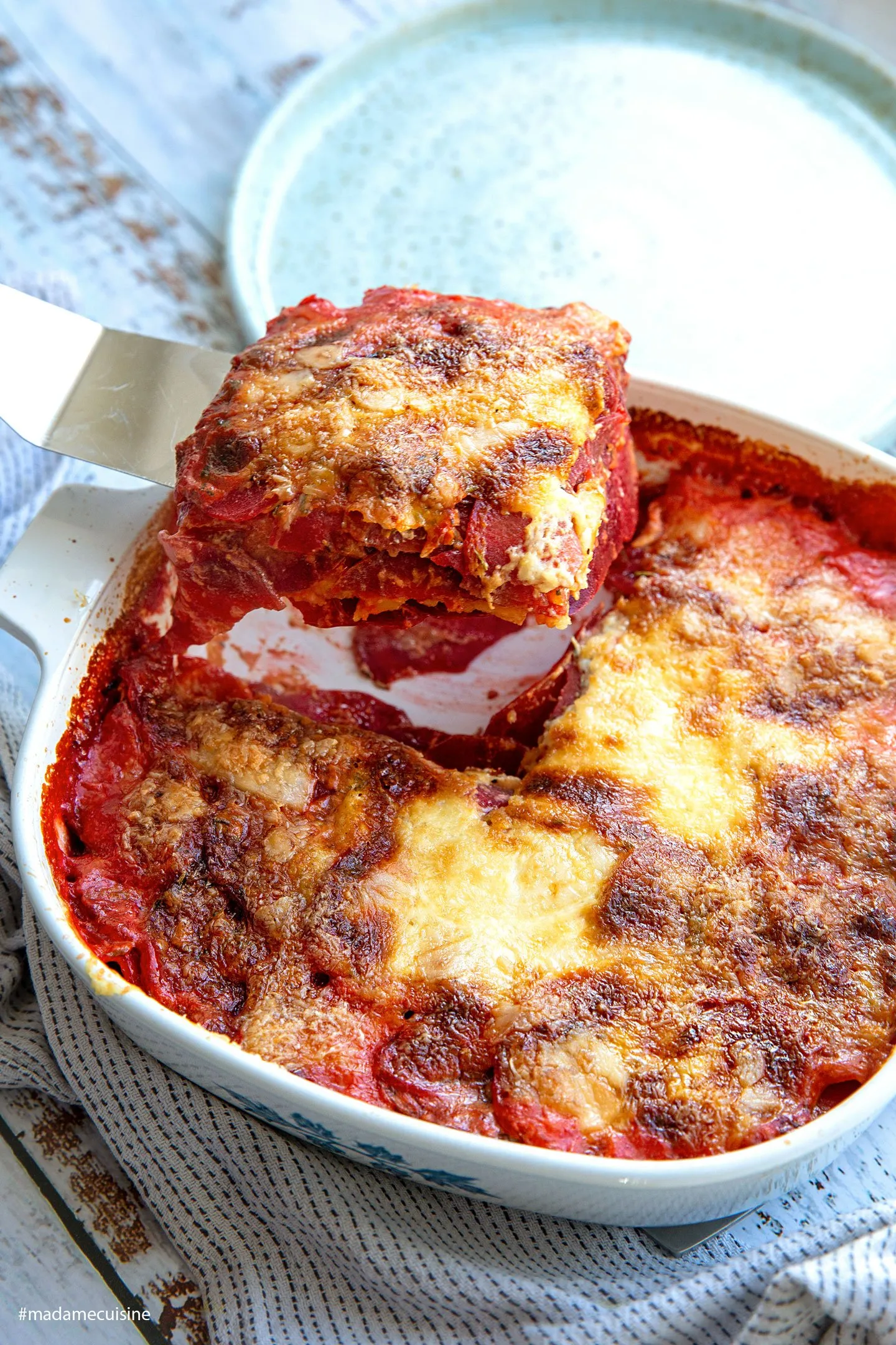 Eine Portion Rote-Bete-Kartoffelgratin auf einem Teller, bereit zum Genießen mit frischem Salat
