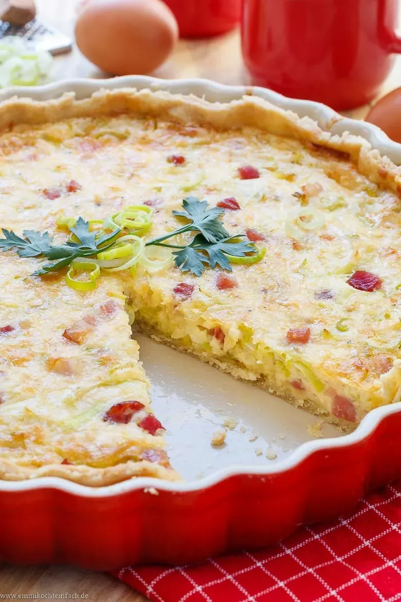 Eine Quiche Lorraine auf einem Holzbrett, serviert mit frischem Salat