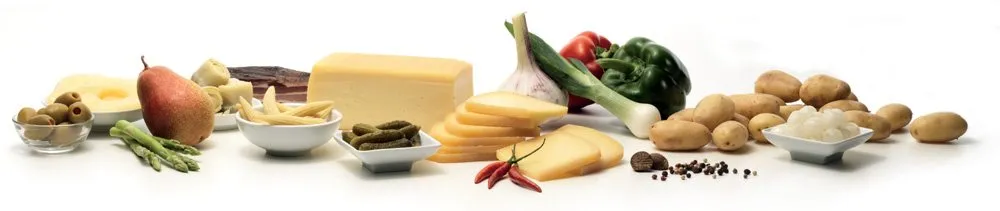 Eine reich gedeckte Raclette-Tafel mit verschiedenen Zutaten wie Käse, Gemüse und Fleisch