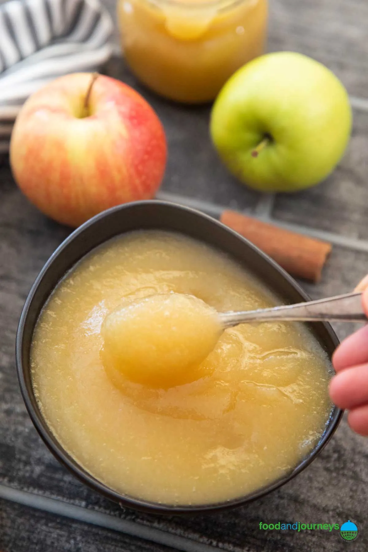 Eine Schüssel mit schnellem Apfelmus, daneben gemischte Apfelsorten.