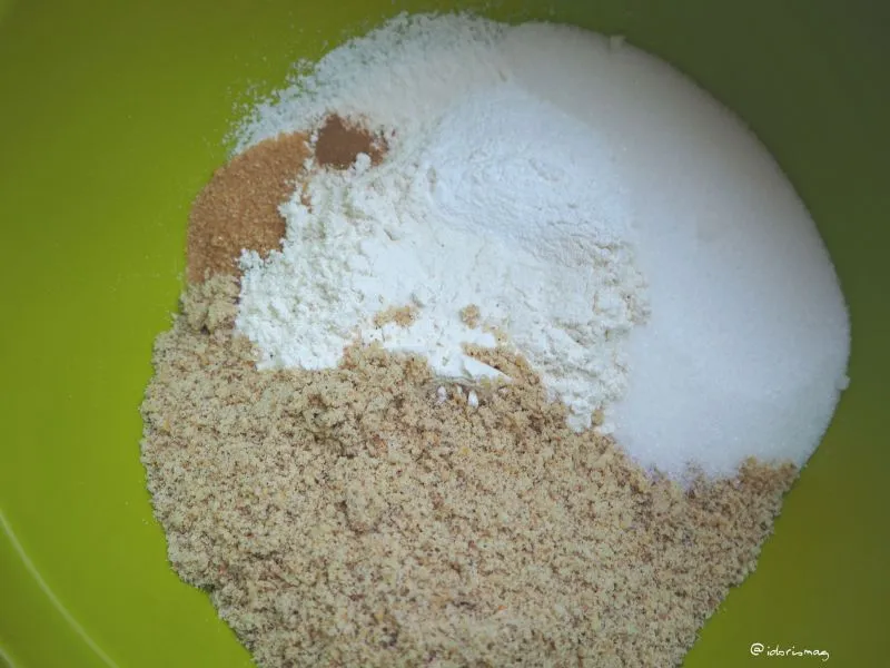 Eine Schüssel mit Zutaten für Muffins, darunter geriebene Karotten und Äpfel, die zu einem Teig vermengt werden