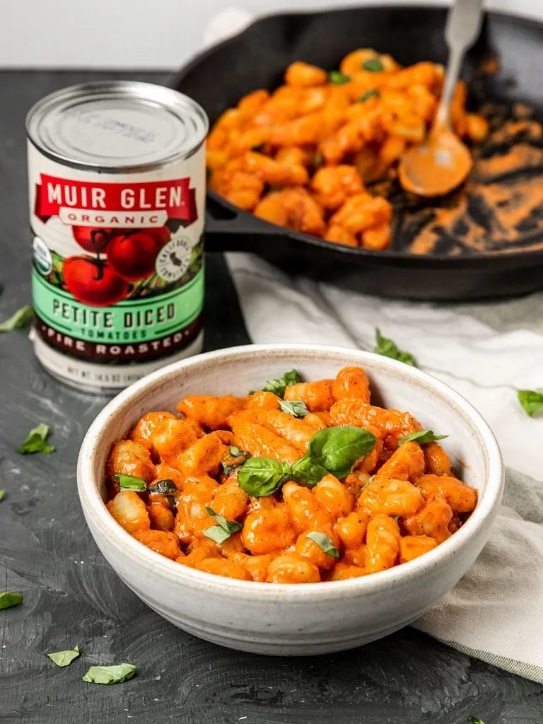 Eine Schüssel vegane Tomatengnocchi mit frischem Basilikum auf einem Tisch