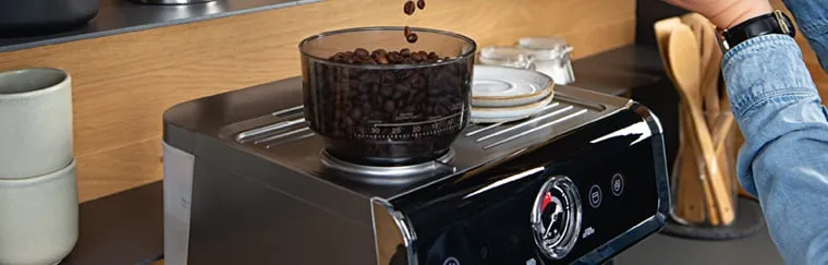 Eine Siebträgermaschine mit integriertem Mahlwerk und frischen Kaffeebohnen.