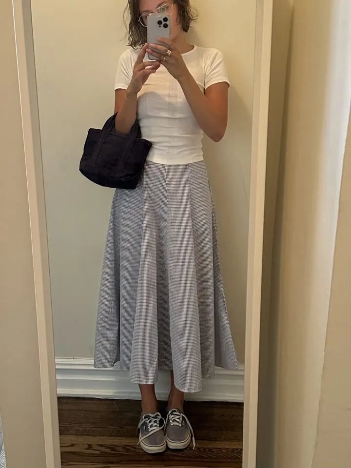 Eine stilvolle Frau posiert in einem schlichten, aber eleganten Muji-Outfit mit Rock und Bluse.