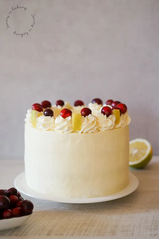Eine wunderschöne, hohe Cranberry-Zitronen-Torte mit Sahnetupfern und frischen Beeren