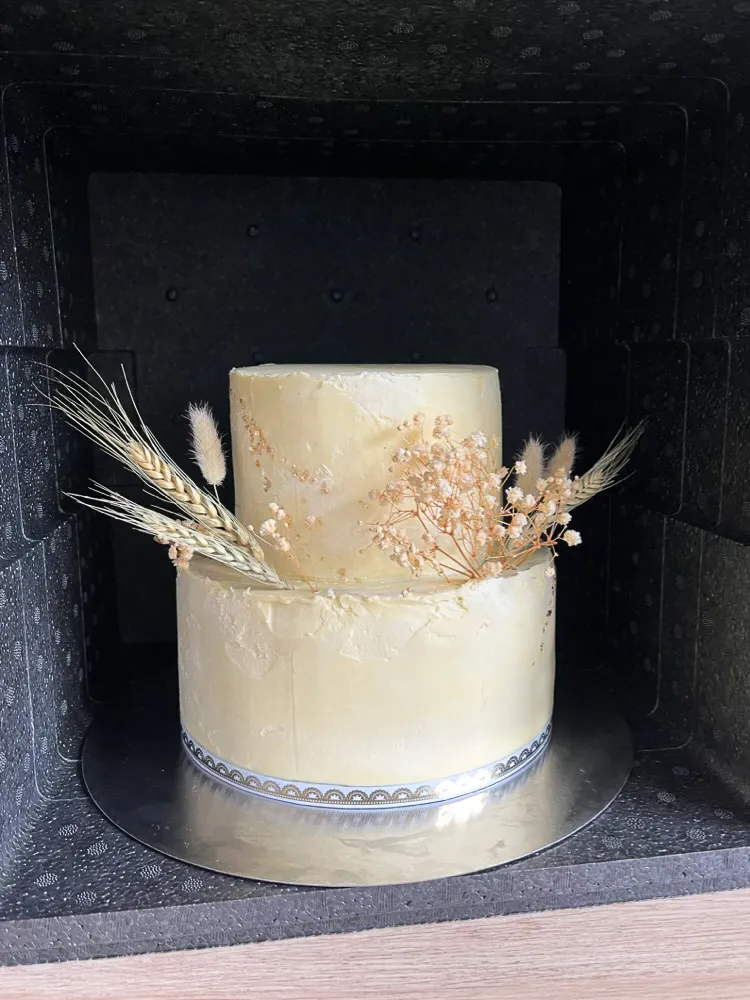 Eine zweistöckige Hochzeitstorte, sicher verpackt in einer Thermobox, bereit für den Transport zur Feierlocation.