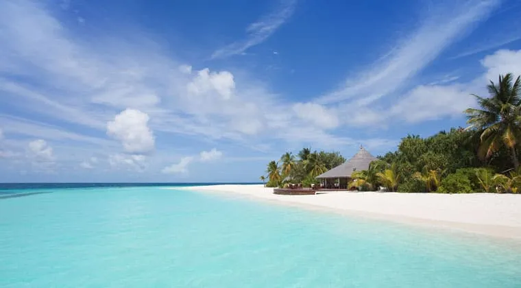 Einladender weißer Sandstrand auf den Malediven mit Palmen und Blick auf das azurblaue Meer