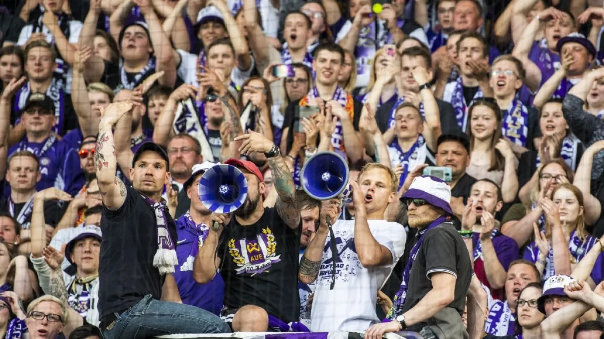 Fans unterstützen die Spieler von Erzgebirge Aue von der Tribüne aus.