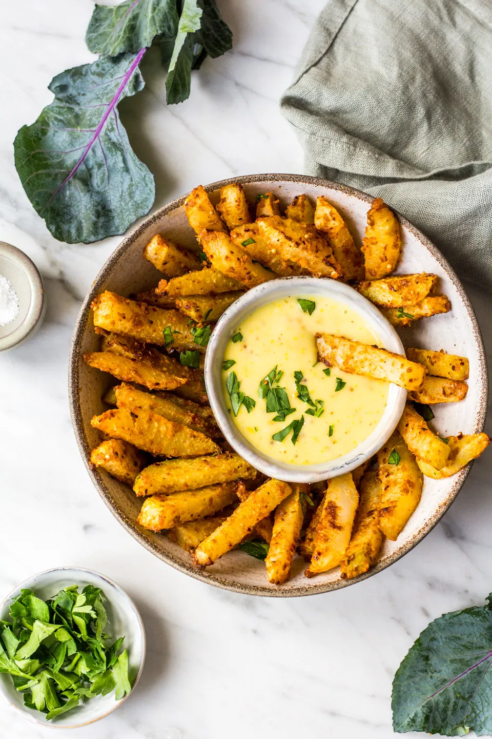 Fertig gebackene Kohlrabi-Pommes auf Zeitungspapier, serviert mit einer cremigen Mayonnaise